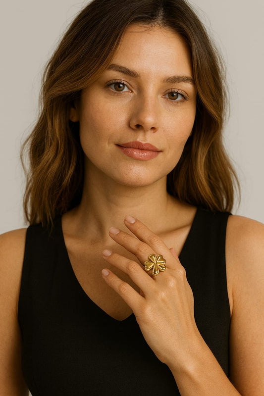 Woman wearing a gold ring on her finger against a neutral background
