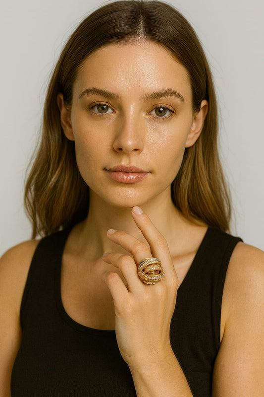 Woman wearing a gold ring on her finger against a plain background